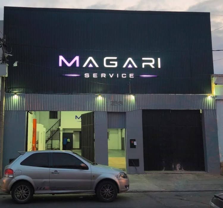 Frente iluminado del taller Magari Service durante la noche